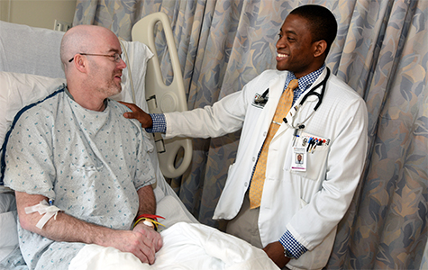 Fourth-year medical student Uzoh Ikpeama checks on a patient, William Gaines of St. Louis, at Barnes-Jewish Hospital. Ikpeama, who was on a rotation at BJH, said he has learned a great deal interacting with patients at the hospital and St. Louis’ VA Medical Centers. 