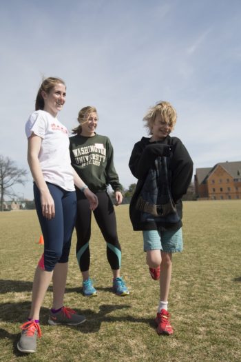 Cofounders Annie Marggraff, left, and Maisie Mahoney work with Kirby Schrand during a Bear Cubs Running Team practice. The club pairs student coaches from the Washington University track and field team with children on the autism spectrum.
